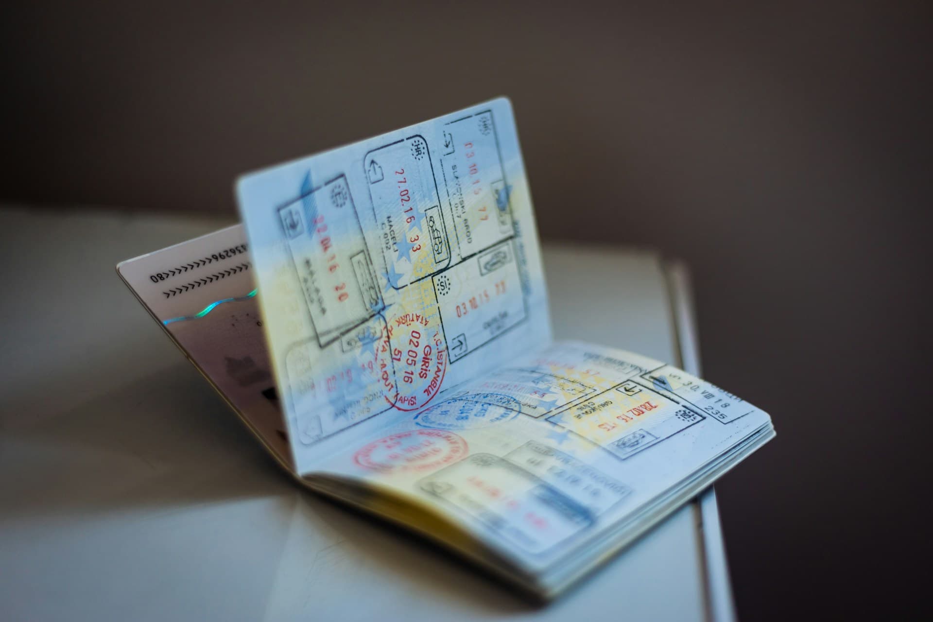A passport lying open on a wooden table with the photo page partially in shadow.
